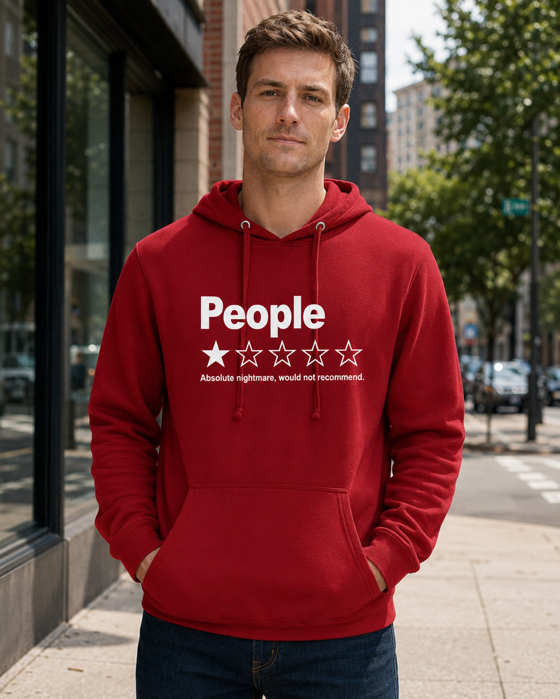 A man wearing a red pullover hoodie with a white graphic print that reads 'People' above a one-star review with five stars, standing on a city sidewalk.