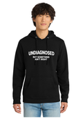 A man wearing a black pullover hoodie with the white printed text 'UNDIAGNOSED BUT SOMETHING AIN'T RIGHT' on the chest, paired with light blue jeans, against a plain white background.