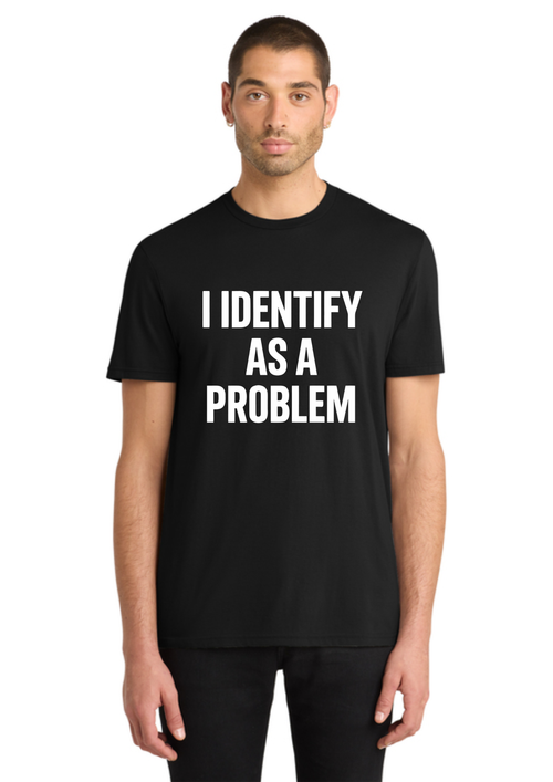 A man wearing a black short-sleeve t-shirt with the text 'I IDENTIFY AS A PROBLEM' printed in bold white capital letters on the chest, set against a plain white background.