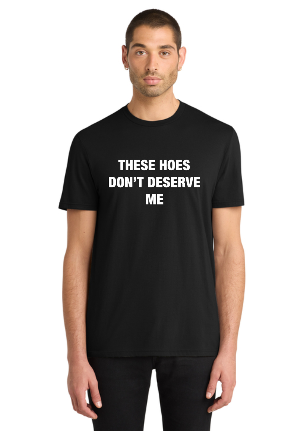 A man wearing a black short-sleeve crewneck t-shirt with the slogan 'THESE HOES DON'T DESERVE ME' printed in bold white capital letters across the chest, set against a plain white background.